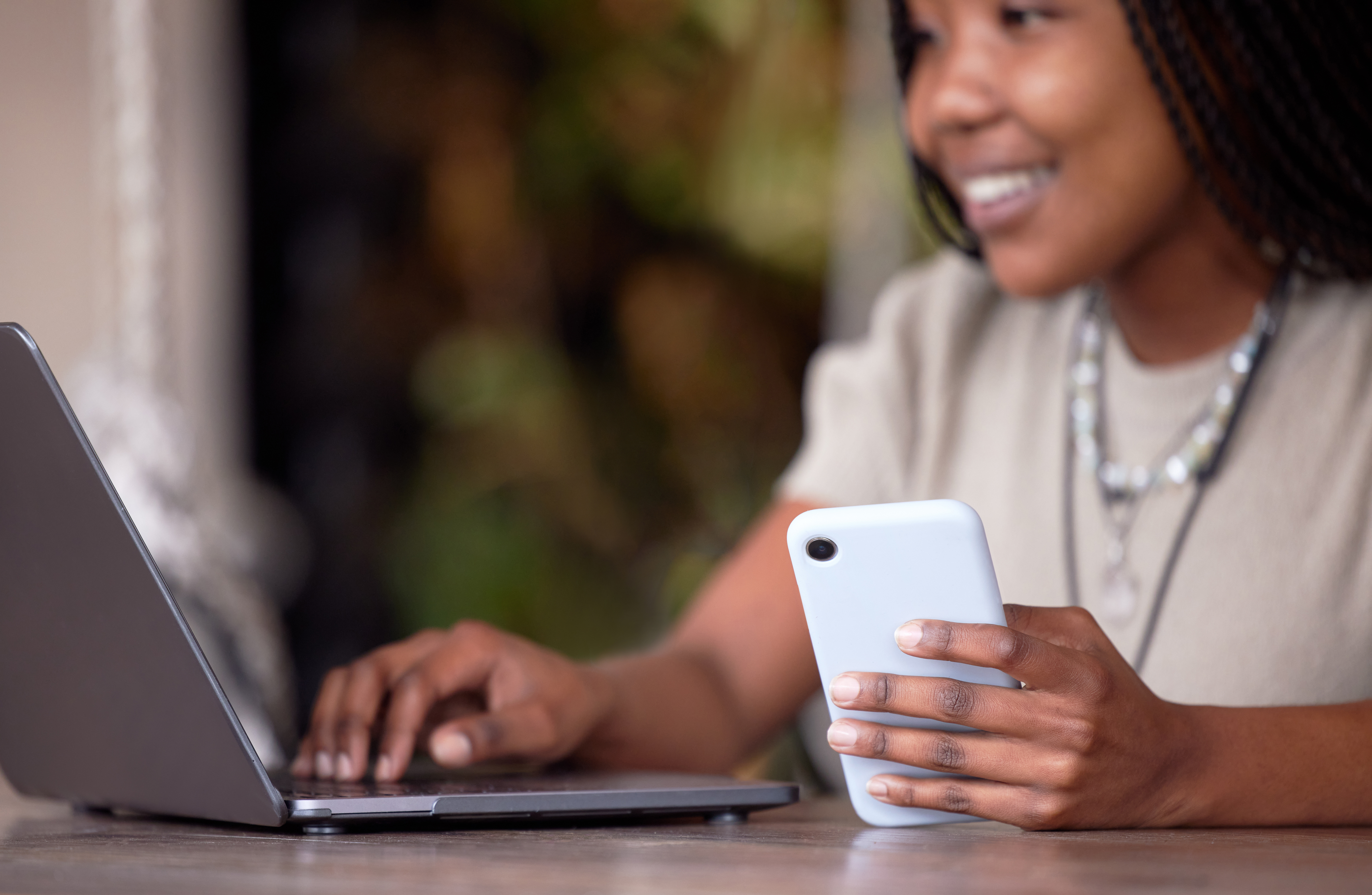 Black woman, phone and laptop in remote work at cafe for communication, social media or chatting. H.